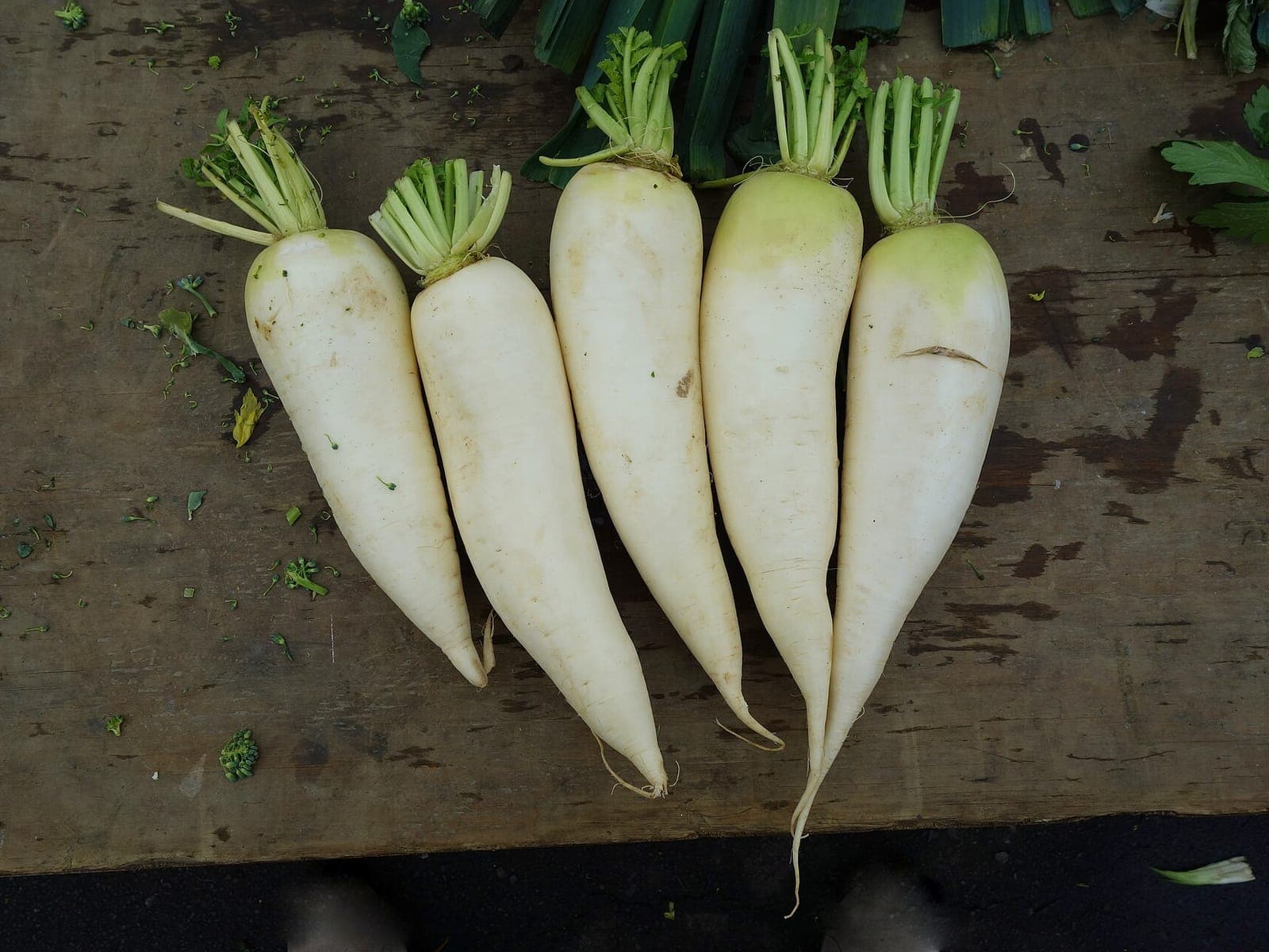 Fresh white radishes with leaves on a market table